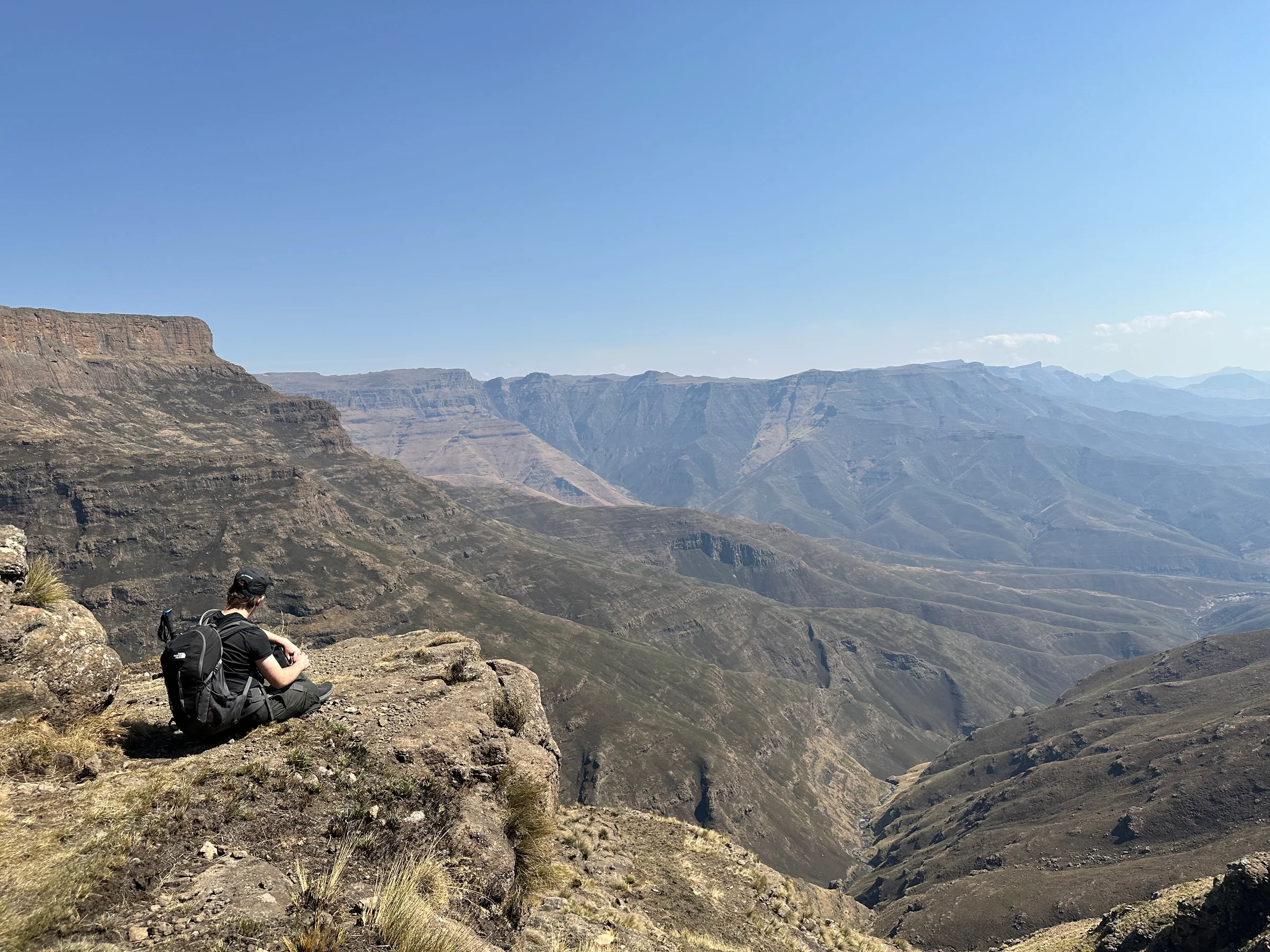A seated hiker looking across a broad mountain valley